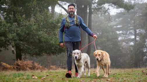 Man in running gear walking two dogs on leads at Hindhead Park